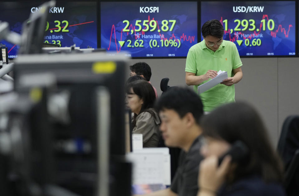 A currency trader passes by screens showing the Korea Composite Stock Price Index (KOSPI), top center, and the foreign exchange rate between U.S. dollar and South Korean won, top right, at the foreign exchange dealing room of the KEB Hana Bank headquarters in Seoul, South Korea, Wednesday, July 12, 2023. Asian shares were mostly higher on Wednesday after stocks advanced on Wall Street as investors awaited an update on U.S. inflation that will hopefully show a smaller increase in pain for everyone.(AP Photo/Ahn Young-joon)