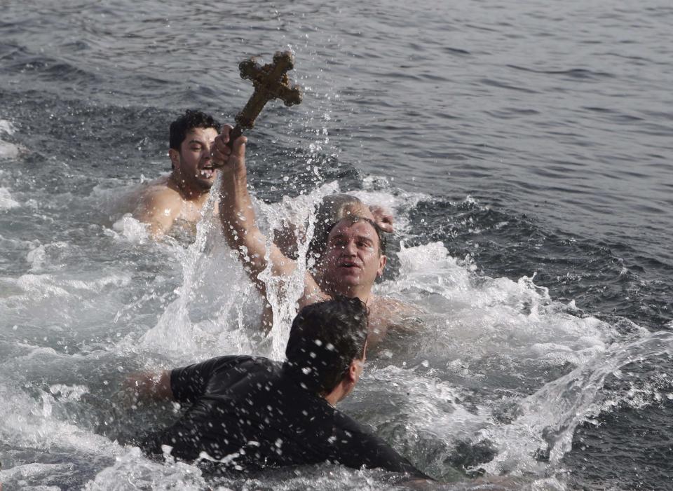 Greek Orthodox faithful Yorgo Aleksandiridis (C) reaches out to retrieve a wooden crucifix as he swims in the Golden Horn in Istanbul January 6, 2014. Greek Orthodox faithful swam to retrieve the wooden crucifix thrown into the Golden Horn in Bosphorus during Epiphany Day celebrations. REUTERS/Osman Orsal (TURKEY - Tags: RELIGION SOCIETY)