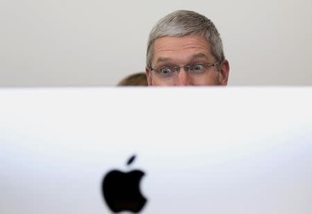 Apple CEO Tim Cook looks at a new IMac after a presentation at Apple headquarters in Cupertino, California October 16, 2014. REUTERS/Robert Galbraith