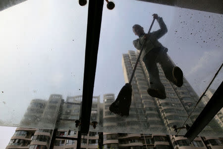 A man cleans the glass roof at the entrance of an apartment building constructed in 2004 after the demolition of old houses, at Guangfuli neighbourhood, in Shanghai, China, April 8, 2016. REUTERS/Aly Song