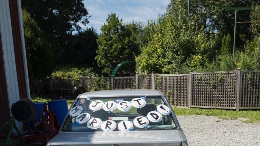 the carmy with a just married sign in the back window spelling out on paper plates and cans of beer and white claw attached