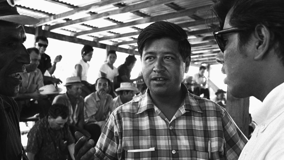 cesar chavez gesturing with his right hand while speaking to another person in the frame