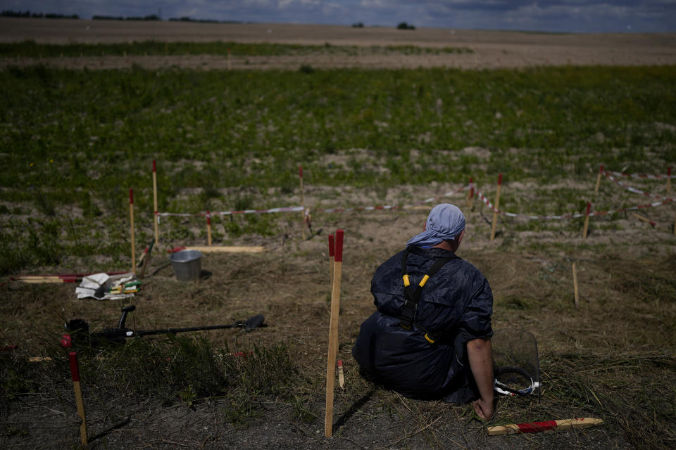 A mine detection worker with the HALO Trust de-mining NGO takes a break while from searching for anti-tank and anti personnel land mines in Lypivka, on the outskirts of Kyiv, Ukraine, Tuesday, June 14, 2022. Russia’s invasion of Ukraine is spreading a deadly litter of mines, bombs and other explosive devices that will endanger civilian lives and limbs long after the fighting stops. (AP Photo/Natacha Pisarenko)