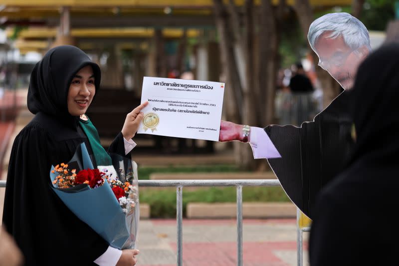 A student stands next to a cardboard figure of Somsak Jeamteerasakul, an exiled Thai academic, before a graduation ceremony, which some students have boycotted because it is led by King Maha Vajiralongkorn, at Thammasat University in Bangkok