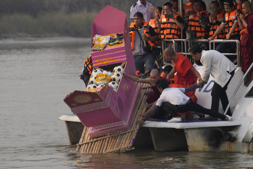 Family members, accompanied by monks and fellow mourners, release the ashes of Duangphet Phromthep in a makeshift boat, along with soccer balls and some of his prized possessions, into the Mekong River in Chiang Rai Province Thailand, Monday, March 6, 2023. Duangphet was one of the 12 boys rescued from a flooded cave in 2018. He died in the U.K. last month. (AP Photo /Sakchai Lalit)