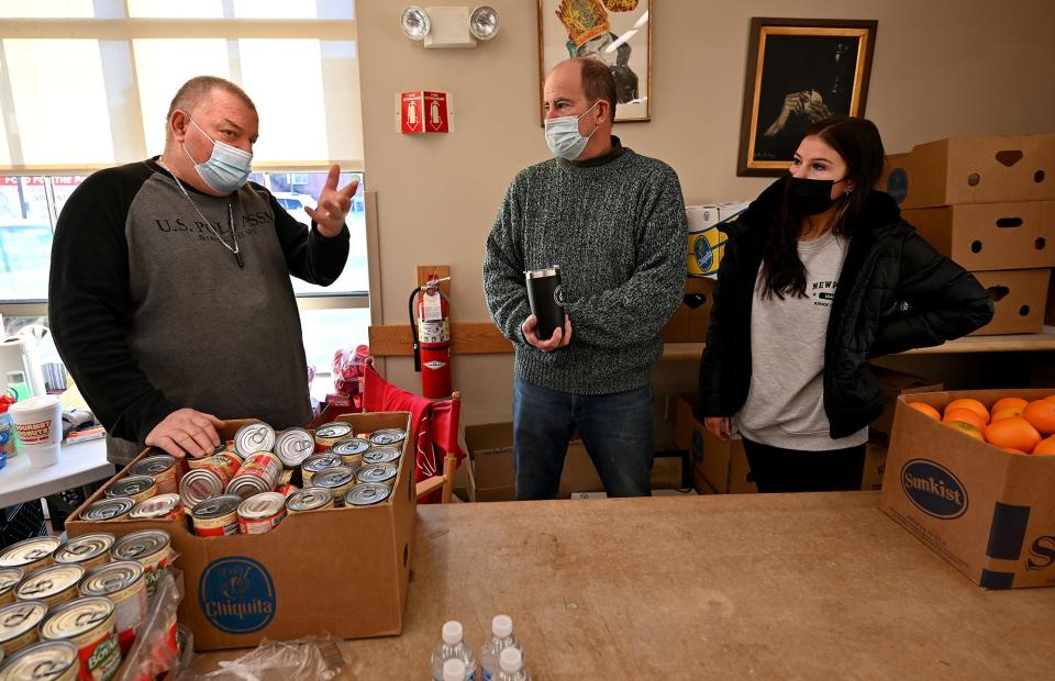 Billy Riley, manager of St. John's Food for the Poor Program, talks with recently arrived father-and-daughter volunteers Patrick and Maddy Carroll, 17, of Bolton.