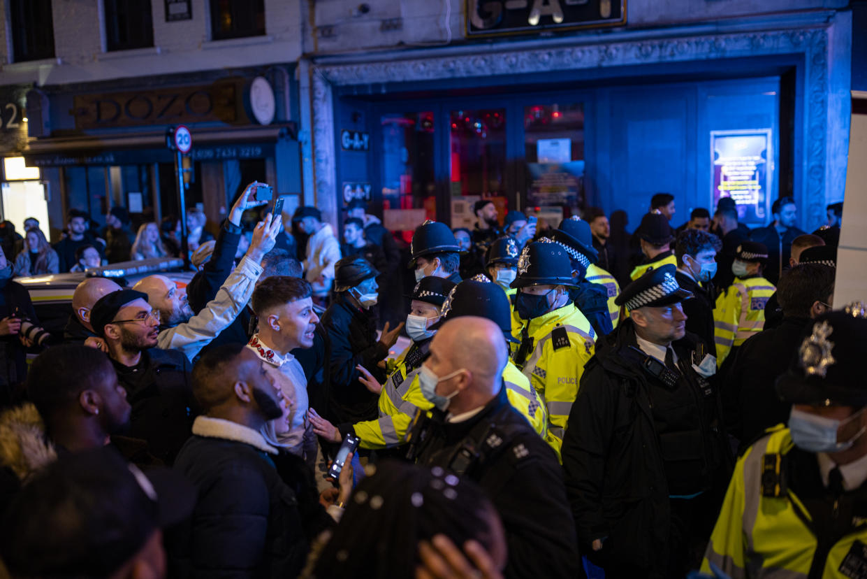 LONDON, ENGLAND - APRIL 16: Police officers attempt to keep the crowd away from a police van after a man was arrester on Old Compton Street in Soho on April 16, 2021 in London, England. Pubs and Restaurants are expecting good business tonight being the first Friday night after Coronavirus lockdown rules were relaxed to allow outside dining and drinking. (Photo by Rob Pinney/Getty Images)