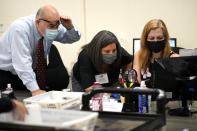 FILE- In this Oct. 26, 2020, file photo, Miami-Dade County Supervisor of Elections Christina White, right, examines signatures on vote-by-mail ballots with members of the Canvassing Board Judge Raul Cuervo, left, and Judge Betsy Alvarez-Zane, center, at the Miami-Dade County Board of Elections in Doral, Fla. Florida will never experience another election meltdown exactly like the one that made the state an international laughingstock in 2000, when after a five-week recount and court battle George W. Bush edged Al Gore and won the presidency. State leaders eliminated computer punchcard ballots, implemented statewide recount laws and made it easy to cast and process ballots before Election Day. (AP Photo/Lynne Sladky, File)