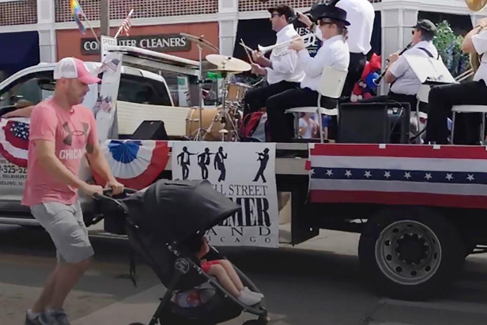 A man runs for cover with a child in a stroller after gunfire was heard at a Fourth of July parade in the Chicago suburb of Highland Park.