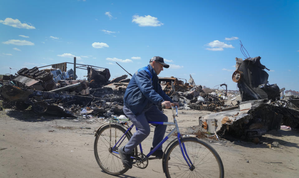 A local residence rides a bike past a destroyed Russian military vehicle in Bucha, on the outskirts of Kyiv, Ukraine, Tuesday, May 10, 2022. (AP Photo/Efrem Lukatsky)