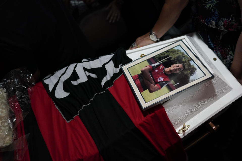 A photo of the young soccer Arthur Vinicius, one of the victims of a fire at a Brazilian soccer academy, is displayed over his coffin during his funeral in Volta Redonda, Brazil, Saturday, Feb. 9, 2019. A fire early Friday swept through the sleeping quarters of an academy for Brazil's popular professional soccer club Flamengo, killing several and injuring others, most likely teenage players, authorities said. (AP Photo/Leo Correa)