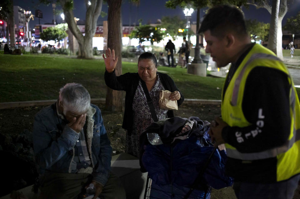 Church volunteers William Fimbres, right, and Lourdes Puerta, center, pray for Luis Carrillo, a homeless man living in MacArthur Park, in Los Angeles, Friday, Oct. 13, 2023. (AP Photo/Jae C. Hong)