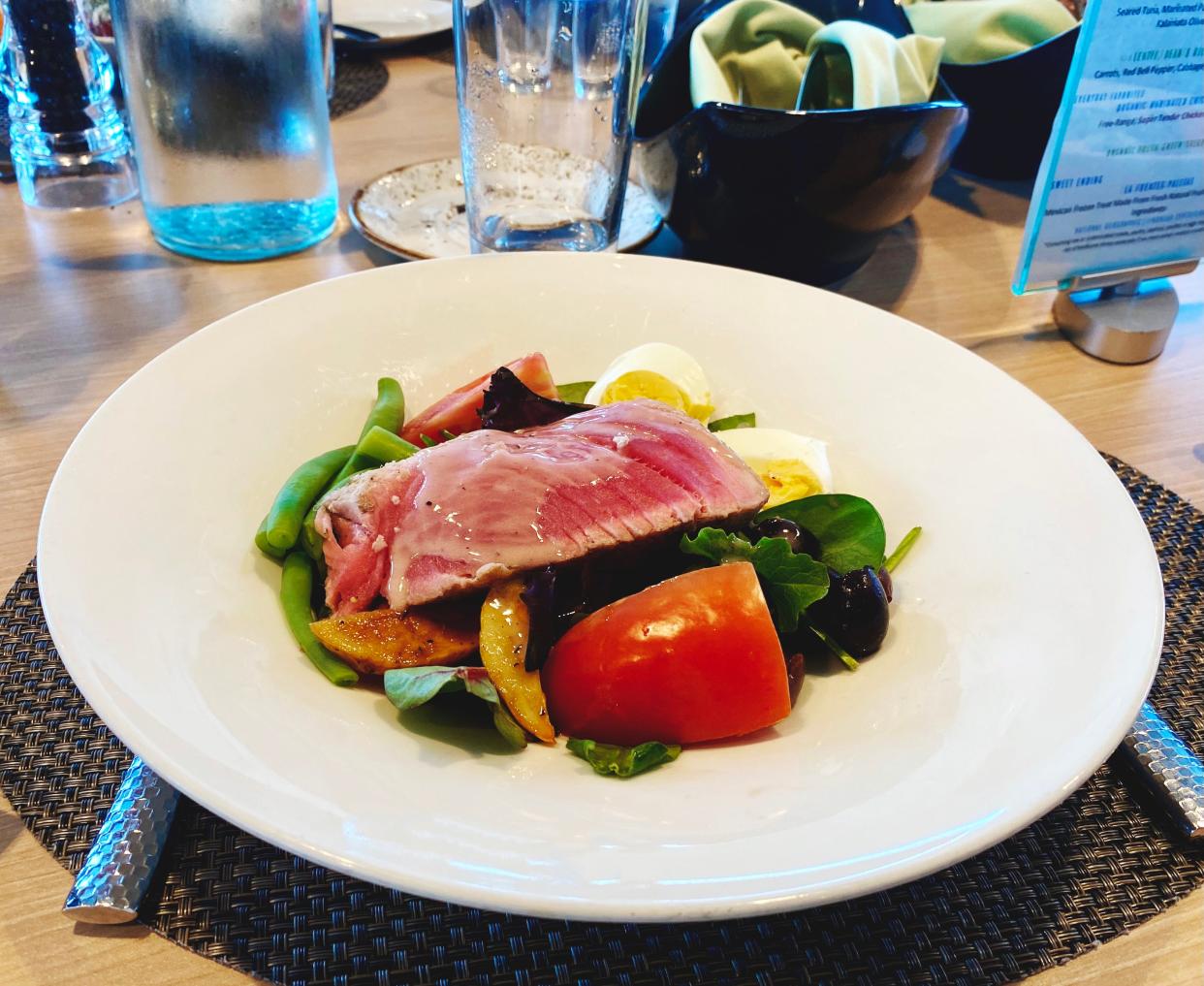 A plate with greens, fish, eggs and tomato is shown.