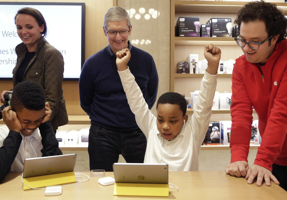 FILE - In this Wednesday, Dec. 9, 2015, file photo, Jaysean Erby raises his hands as he solves a coding problem as Apple CEO Tim Cook watches from behind at an Apple Store, in New York, as Apple hosted Hour of Code events around the world as part of Computer Science Education Week. Despite loudly touted efforts, the tech industry is making very little progress in diversifying its workforce, especially in technical and leadership positions. Companies are spending a lot of time and money on improving diversity, from outreach at high schools and historically black colleges to internship and mentoring programs to sponsorships for coding boot camps to bias training and support groups. So far, to little avail. (AP Photo/Mark Lennihan, File)