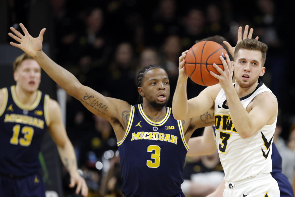 Iowa guard Jordan Bohannon grabs a loose ball in front of Michigan guard Zavier Simpson (3) during the first half of an NCAA college basketball game Friday, Feb. 1, 2019, in Iowa City, Iowa. (AP Photo/Charlie Neibergall)