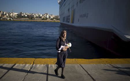 A migrant woman holds a child following their arrival onboard the Eleftherios Venizelos passenger ship at port of Piraeus near Athens, Greece, August 29, 2015. REUTERS/Stoyan Nenov