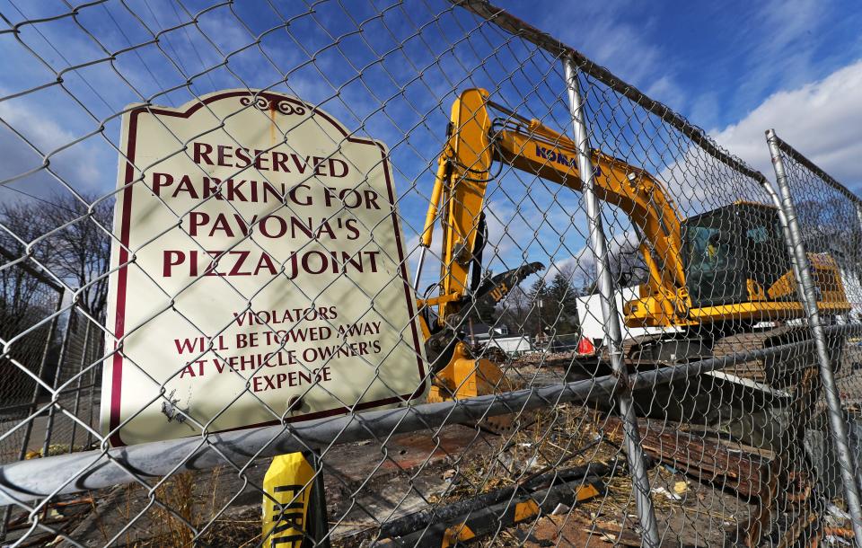 A sign marking a parking spot reserved for Pavona's Pizza Joint stands behind a chainlink fence as cleanup resumes. Mark Mickey, co-owner of Pavona's Pizza Joint and Mickey's Irish Pub in Cuyahoga Falls, has been charged with arson in the fire that destroyed his pizza shop last October.