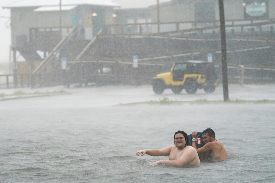 People play in a flooded parking lot at Navarre Beach, Tuesday, Sept. 15, 2020, in Pensacola Beach, Fla. Hurricane Sally is crawling toward the northern Gulf Coast at just 2 mph, a pace that's enabling the storm to gather huge amounts of water to eventually dump on land. (AP Photo/Gerald Herbert)