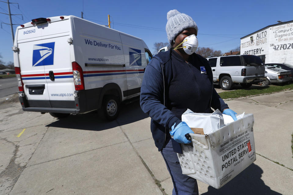 Image: A United States Postal worker makes a delivery with gloves and a mask in Warren, Mich (Paul Sancya / AP file)