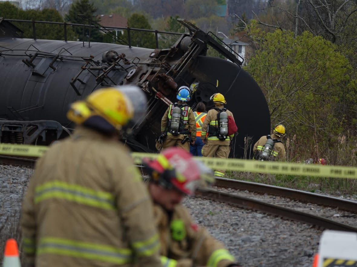 Firefighters examine a derailed train near Bath Road in Kingston on May 5, 2023. Officials say one of the cars was transporting an industrial acid called adipic acid and experienced a 