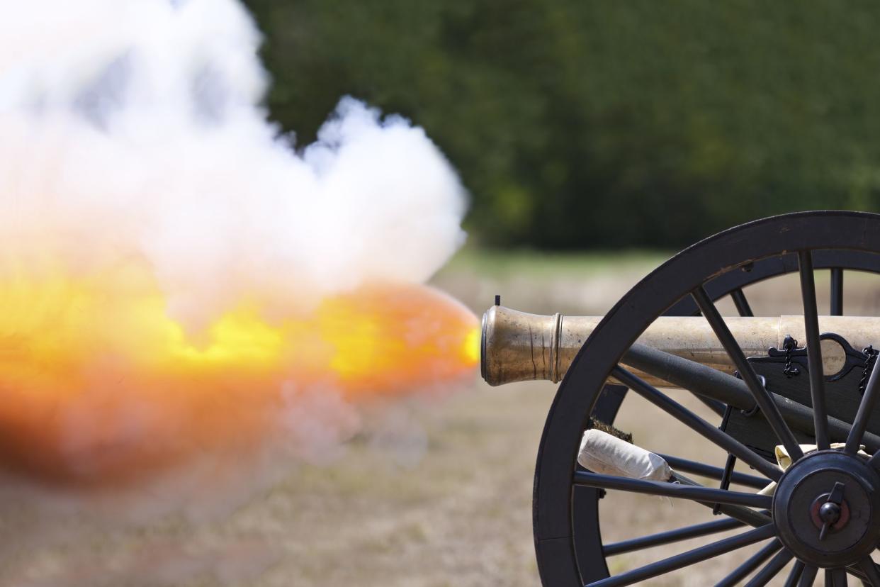 A close up shot of a Civil War cannon firing at a civil war re-enactment.