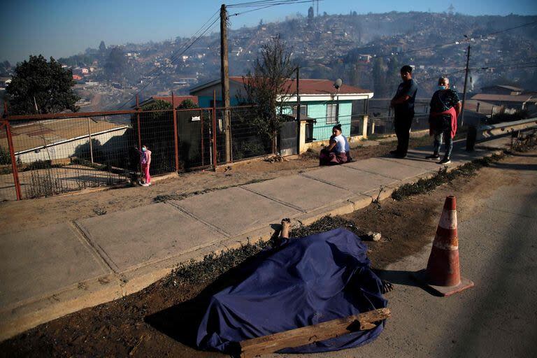 Un cuerpo cubierto yace en la calle luego de un incendio que afectó los cerros de Viña del Mar