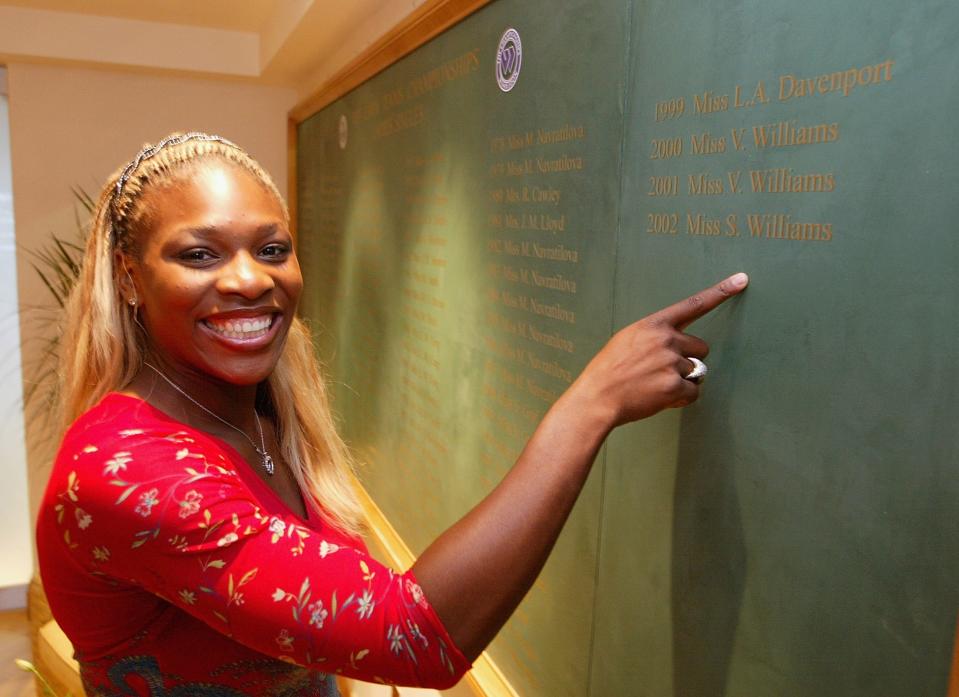 Serena Williams points to her name on the Women's Singles Champions roll of honor at Wimbledon.