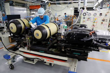 An employee of Toyota Motor Corp. works next to the unit of fuel cell stack and hydrogen tanks of a Mirai fuel cell vehicle (FCV) on it's assembly line at the company's Motomachi plant in Toyota, Aichi prefecture, Japan, May 17, 2018. REUTERS/Issei Kato
