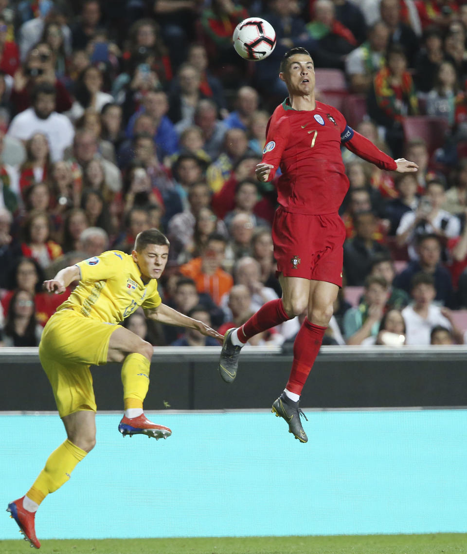 Portugal's Cristiano Ronaldo, right, challenges for the ball with Ukraine's Vitaliy Mykolenko during the Euro 2020 group B qualifying soccer match between Portugal and Ukraine at the Luz stadium in Lisbon, Friday, March 22, 2019. (AP Photo/Armando Franca)