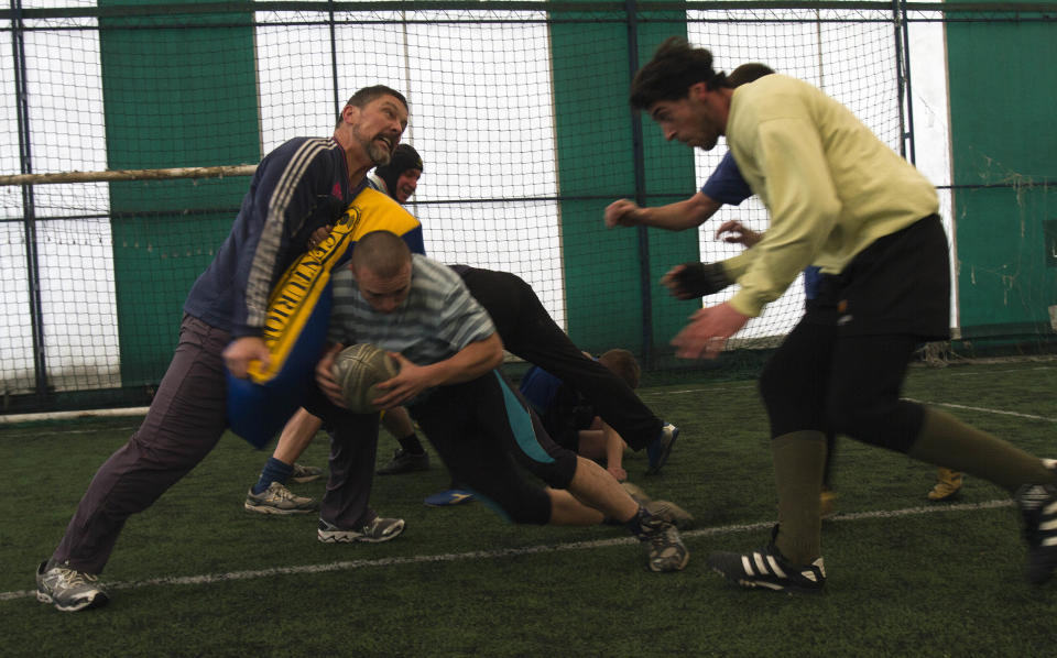 In this photo taken on Sunday, Feb. 2, 2014, members of the Kosovo Roosters Rugby team train in an indoor pitch in Mitrovica, Kosovo. They've been roughing each other up for almost a century without any rules. But, now Serbs and Albanians are tackling a new form to deal with old enmities. Spurred by a group of aid workers they are learning to work together through a sport that is all about gaining territory: rugby. In Mitrovica, a city that has come to symbolize the ethnic split, youths from both side of the divide gather to train and follow instructions from their French, Irish and American trainers. (AP Photo/Visar Kryeziu)