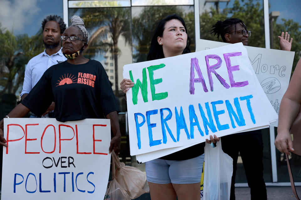 LGBTQ activists hold signs that read: We are permanent, and People over politics.