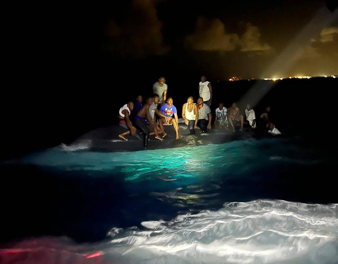 In this photo provided by the Royal Bahamas Defense Force, survivors sit on a capsized boat as they are about to be rescued near New Providence in the Bahamas, early Sunday, July 24, 2022. Bahamas Prime Minister Philip Brave Davis said in a statement that the dead included 15 women, one man and an infant. (Royal Bahamas Defense Force via AP)