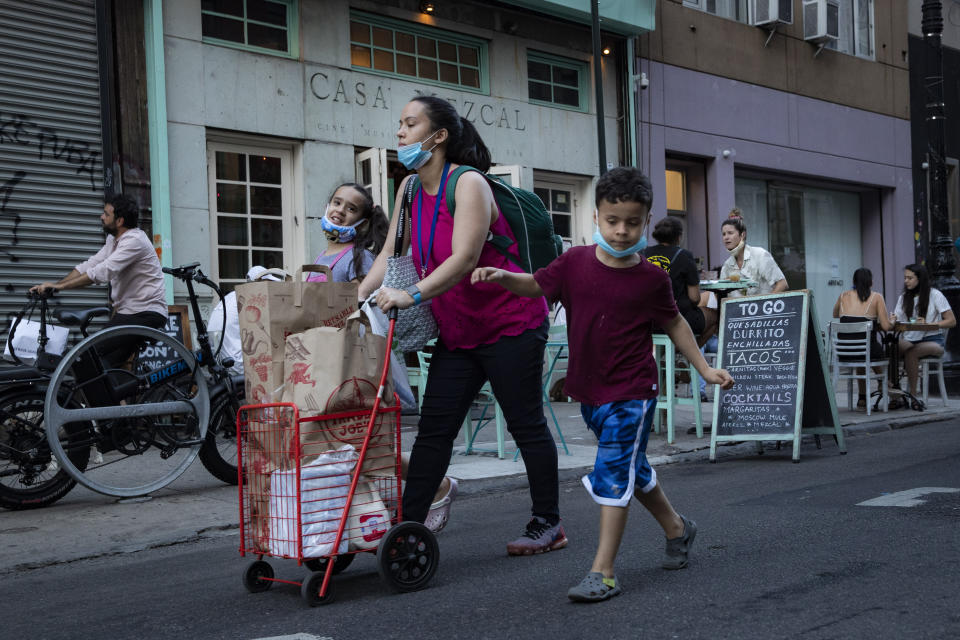 Pedestrians pass customers dining outside Casa Mezcal, Monday, June 22, 2020, in New York. New York City ventured into a crucial stage of reopening as stores let people in Monday, offices brought workers back, restaurants seated customers outdoors and residents both welcomed and worried about rebounding from the nation's deadliest coronavirus outbreak. (AP Photo/John Minchillo)