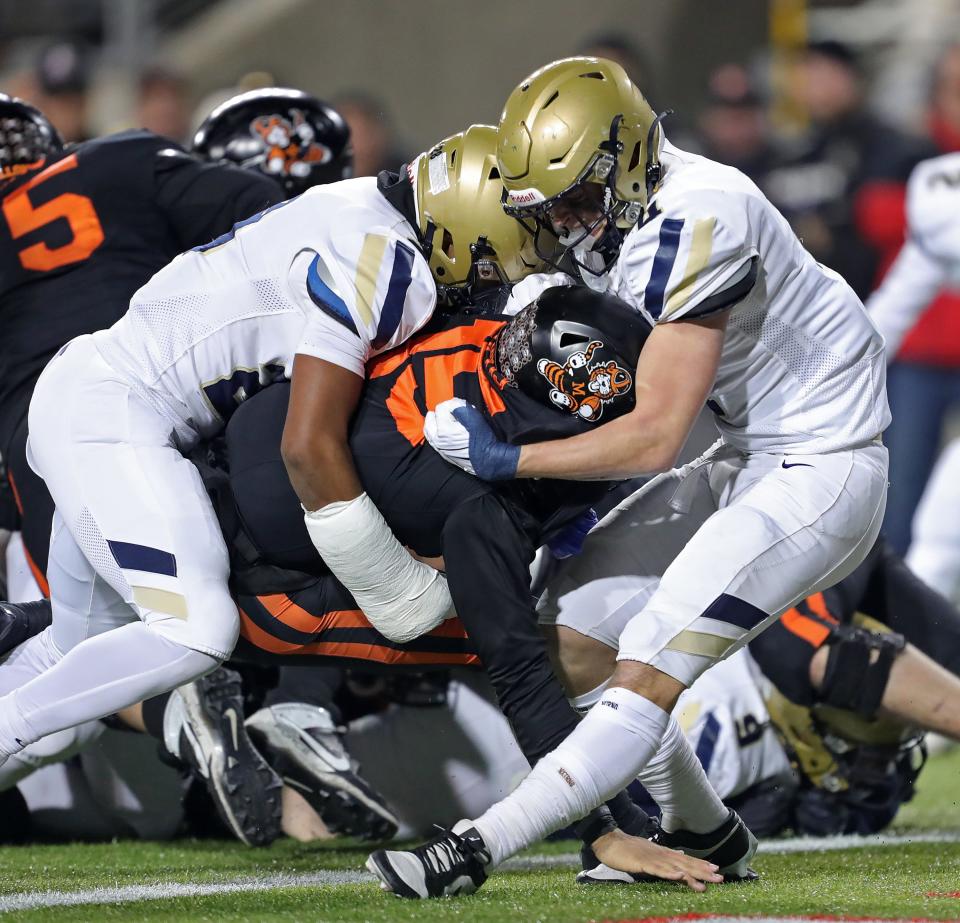 Hoban linebacker Tanner Mintz, right, and tackle Cartier Williams, left, bring down Massillon quarterback DaOne Owens in the end zone for a safety during the first half.