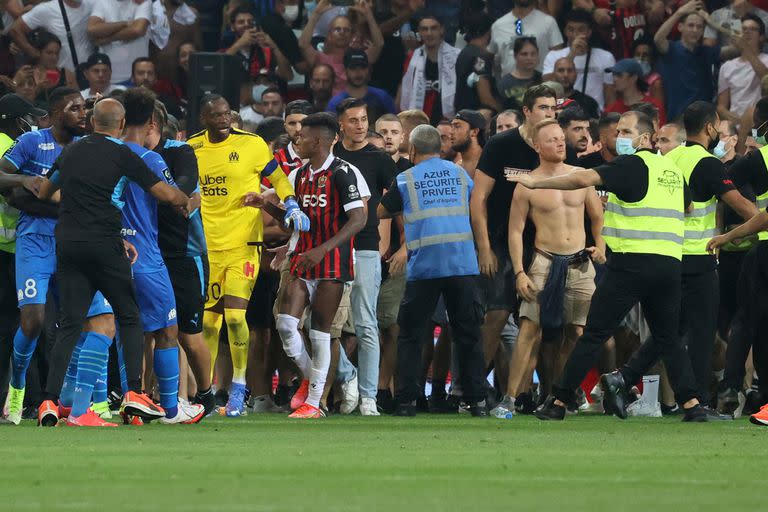 Los aficionados intentan invadir el campo durante el partido de fútbol francés L1 entre OGC Nice y Olympique de Marseille (OM) en el estadio Allianz Riviera en Niza, sur de Francia el 22 de agosto de 2021. El partido de la Ligue 1 francesa entre Niza y Marsella se detuvo el 22 de agosto de 2021, cuando la afición local invadió la cancha y enfrentó airadamente al jugador contrario Dimitri Payet. Un periodista de la AFP en el juego dijo que los problemas estallaron en el minuto 75 cuando la estrella del Marsella Payet, que había sido atacada