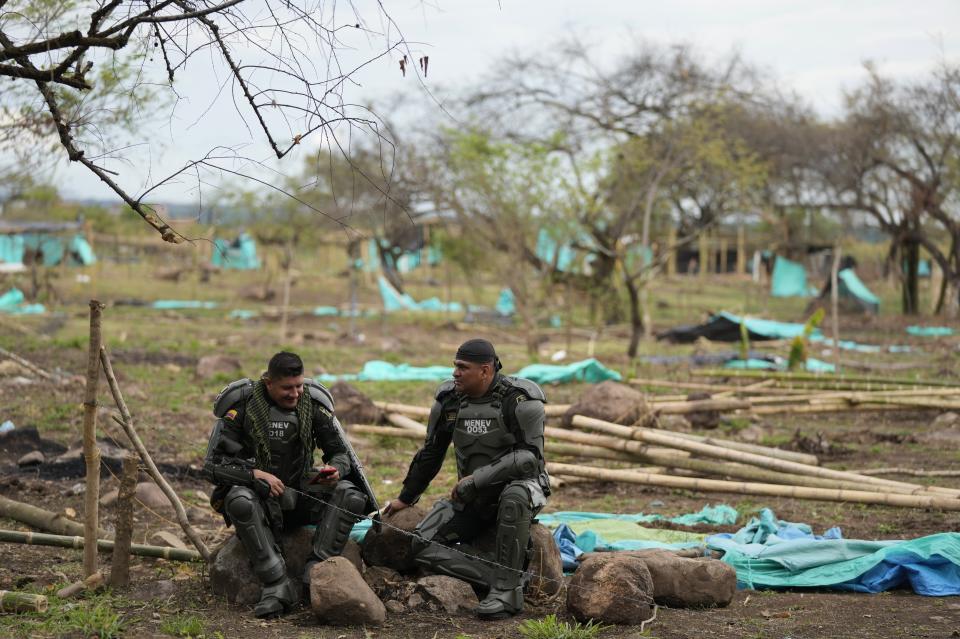 Policías descansan después de desalojar a los ocupantes ilegales de un terreno en Neiva, Colombia, el miércoles 28 de septiembre de 2022. Unas 50 hectáreas fueron ocupadas por al menos 500 familias hace casi dos meses. (Foto AP/Fernando Vergara)