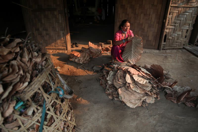 A woman prepares leaves for the roof of her house in the Kayan village where people, who fled from Myanmar during the 1990s war between Myanmar's army and ethnic army groups, live in Mae Hong Son