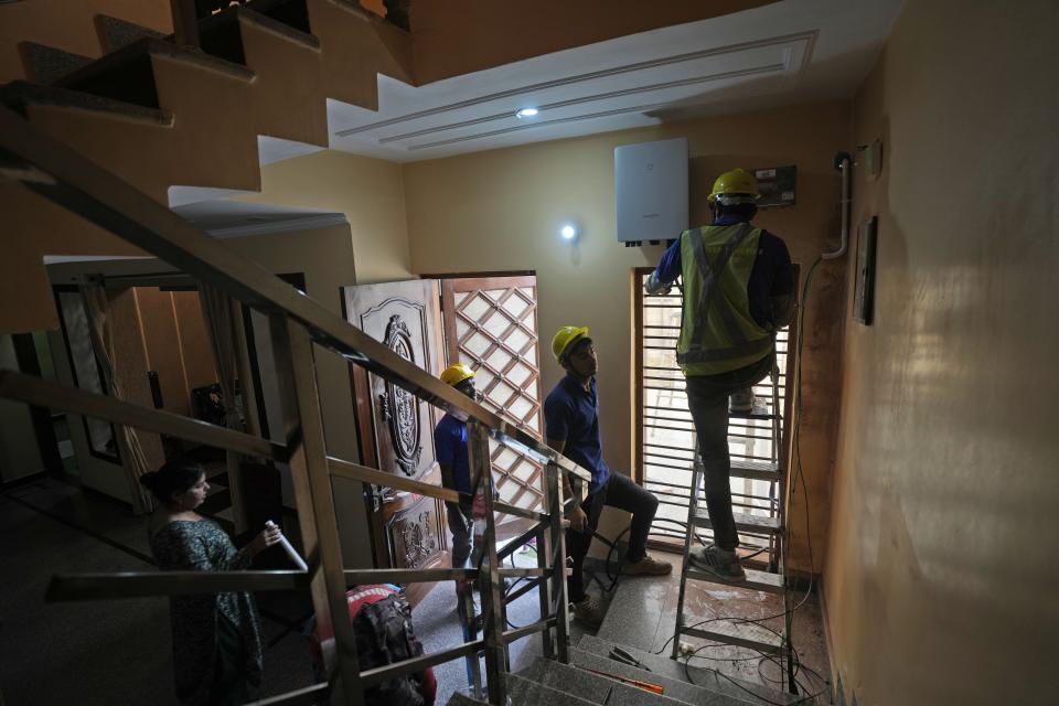 Workers of Solar Square work on the cables for connecting the rooftop solar panels through a meter at a residence in Gurugram on the outskirts of New Delhi, India, Tuesday, Feb. 20, 2024. India is renewing its push to add rooftop solar to meet the needs of a fast-growing nation that's hungry for energy. (AP Photo/Manish Swarup)