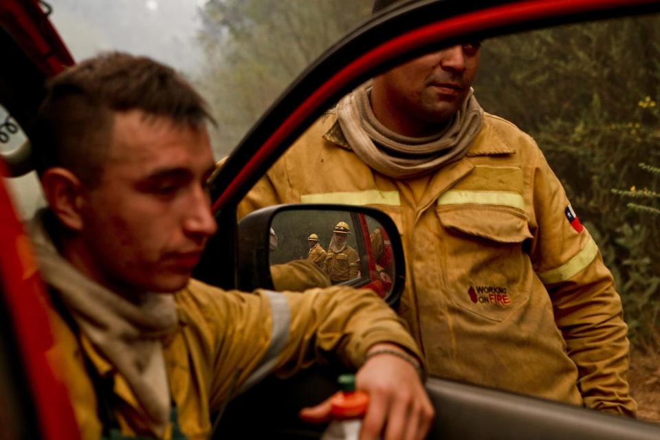 In this Friday, Jan. 27, 2017 photo, firefighters takes a break from digging trenches, as wildfires threaten Florida, a community of Concepcion, Chile. More than 20,000 people, including firefighters and experts from more than a dozen countries, have battled wildfires that President Michelle Bachelet has called the worst forest disaster in Chile's history. (AP Photo/Esteban Felix)