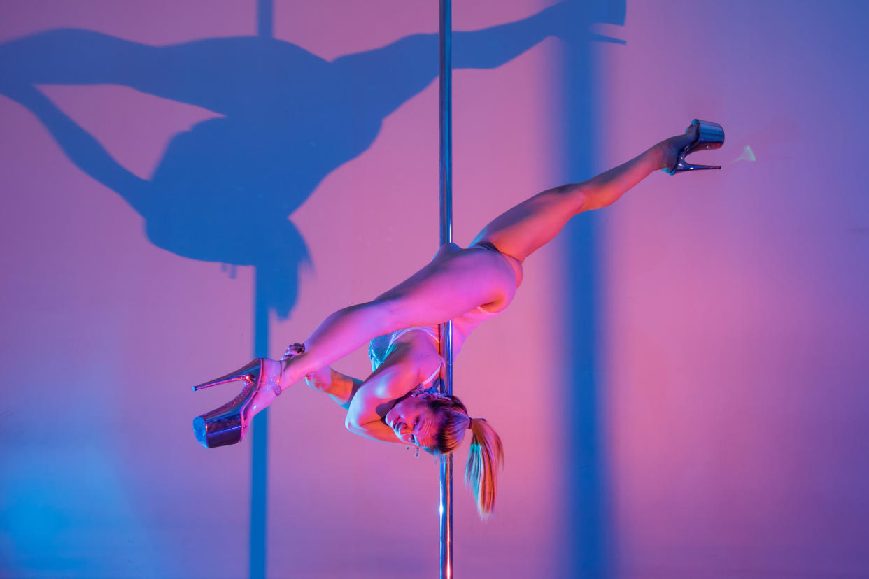 Here, the author is doing an advanced-level pole dance move called the choker split. (Photo: Alloy Images)