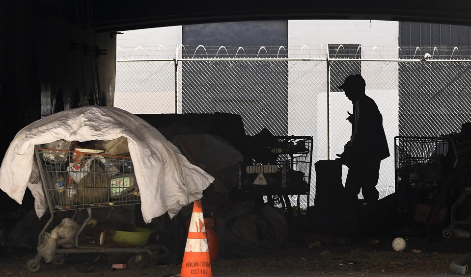 FILE - In this May 21, 2020 file photo, a man is seen at a homeless encampment that sits under Interstate 110 near Ramirez Street during the coronavirus outbreak in downtown Los Angeles. A coalition in California is proposing legislation to boost taxes on wealthy multi-national corporations to raise more than $2 billion a year to end homelessness. Supporters say Assembly Bill 71, if approved, would "reinvent" the state's approach to solving homelessness. (AP Photo/Mark J. Terrill, File)