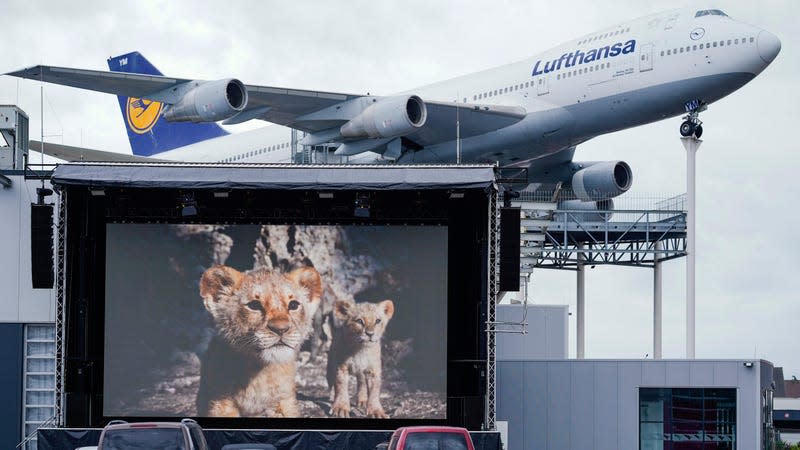 30 April 2020, Rhineland-Palatinate, Speyer: Cars are parked on a parking lot in front of a screen in the drive-in cinema of the Technik Museum Speyer. In the background a model of a Boeing 747 airplane can be seen as an exhibit.