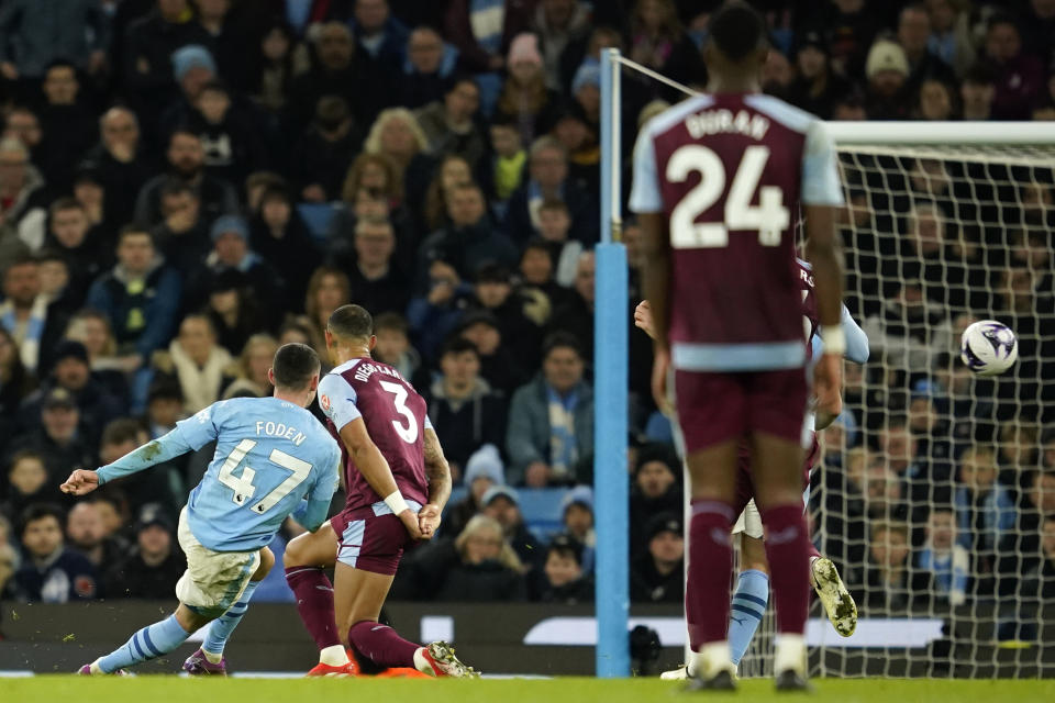 Manchester City's Phil Foden, left, scores his team's fourth goal, during the English Premier League soccer match between Manchester City and Aston Villa at the Etihad Stadium in Manchester, England, Wednesday, April 3, 2024. (AP Photo/Dave Thompson)