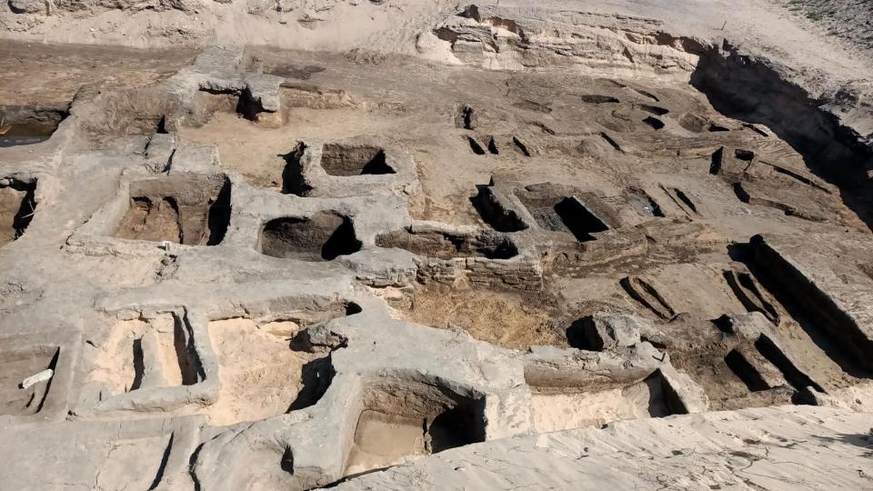 An excavation site showing many rectangular holes in the desert