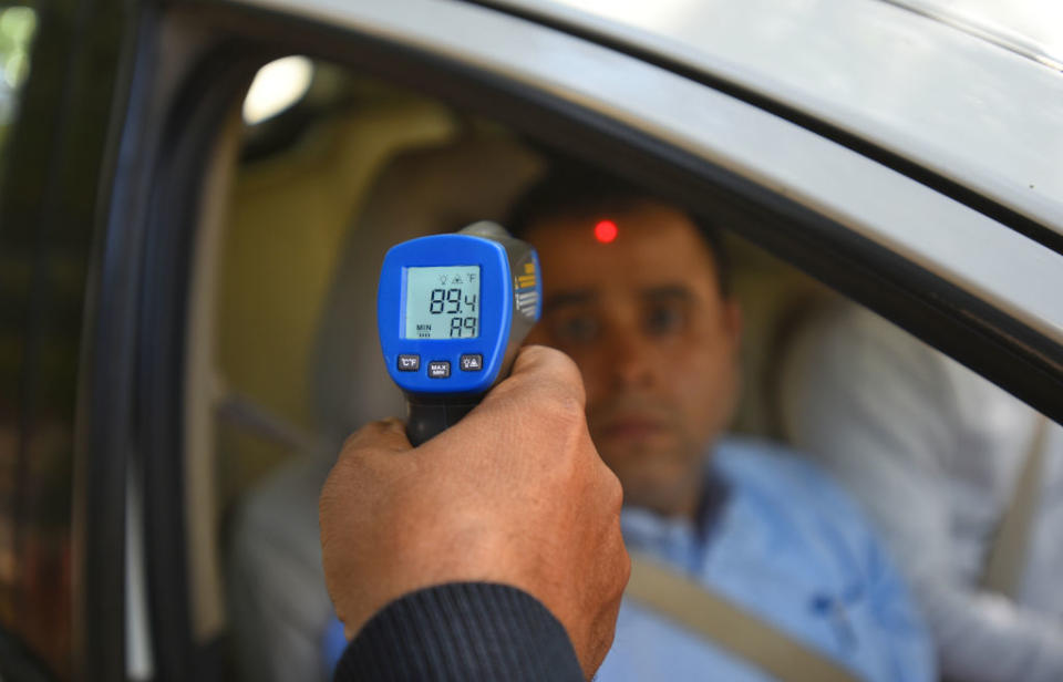 A security guard holds up an infrared thermometer to screen passengers in a car, as a precautionary measure against coronavirus (COVID-19), at Barakhamba Road on March 9, 2020 in New Delhi, India. | Photo by Amal KS/Hindustan Times