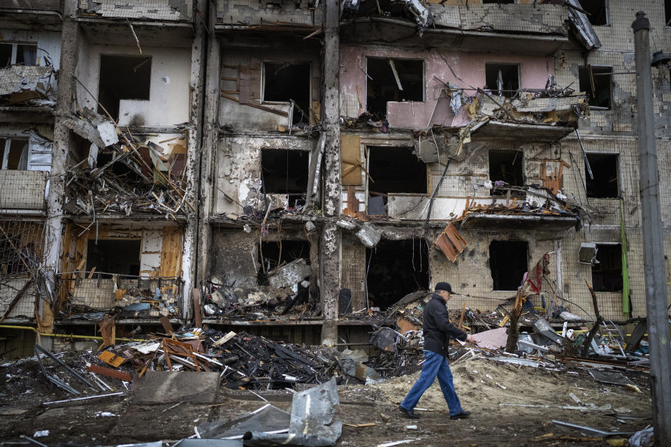 A man walks past a building damaged following a rocket attack the city of Kyiv, Ukraine, Friday, Feb. 25, 2022. (AP Photo/Emilio Morenatti)