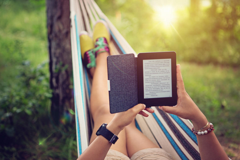 Beautiful girl is reading e-book in the hammock.