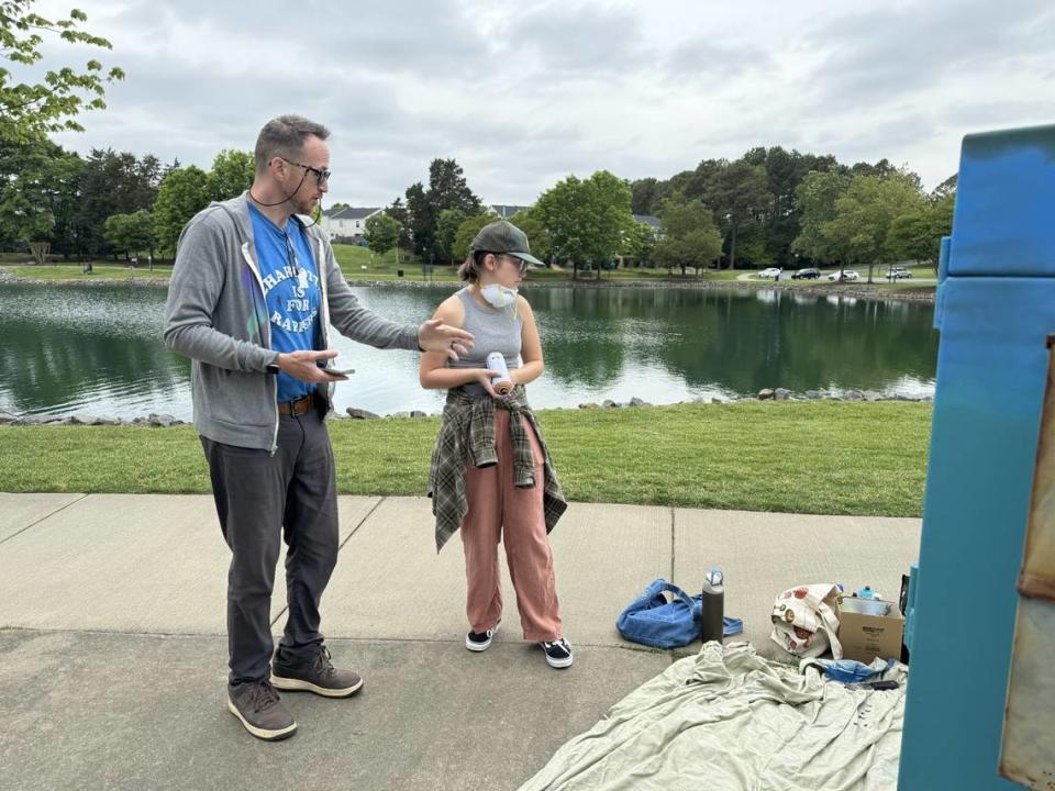 Mike Wirth, a muralist and art professor at Queens University of Charlotte, consults with student Allison Morton on a utility box design at Pineville Lake Park.