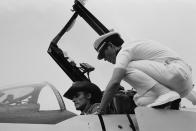 <p>Dennis Hopper jumps into the cockpit and gets a look behind the wheel of an aircraft carrier battleship in 1976. </p>