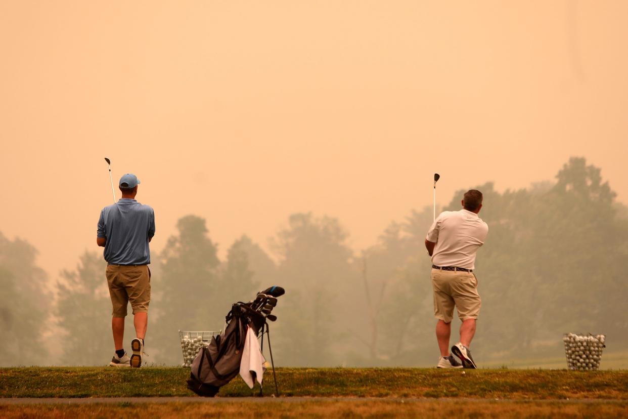 Golfers watch their shots at the driving range at Valley Country Club in Sugarloaf, Pennsylvania, as smoke from wildfires in Canada fill the air on Wednesday (John Haeger/Standard-Speaker via AP)